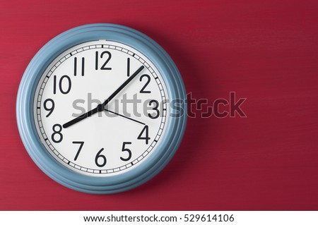 Blue wall clock on red grunge background. Royalty-Free Stock Photo #529614106