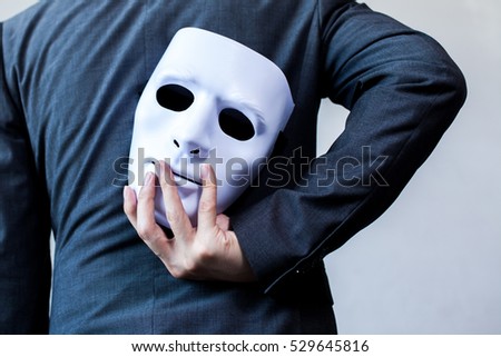 Business man carrying white mask to his body indicating Business fraud and faking business partnership Royalty-Free Stock Photo #529645816