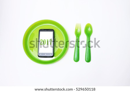 Eating smart phone on set of fork,spoon and dish wood for year 2017 on white background. 