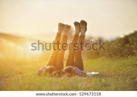 Two happy asian children lying on green grass outdoors and rise legs up in spring park,Fun concept. Royalty-Free Stock Photo #529673158