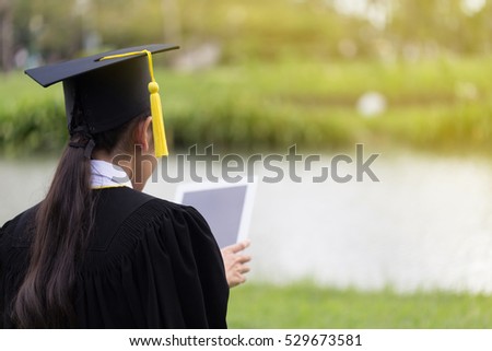 Women Student Graduate playing tablet in her hand feeling relaxing and so happiness in Commencement day