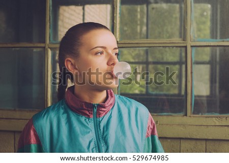 The girl in the nineties inflates chewing bubble Royalty-Free Stock Photo #529674985