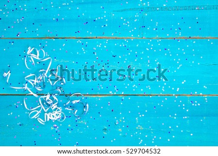 Colorful holiday confetti and ribbon border on blank antique rustic teal blue textured wood background sign; color copy space for text with pink, purple, blue decorations