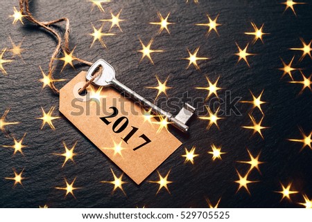 Metal key with 2017 year tag. Festive picture with lightening golden stars.