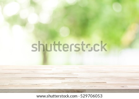 Wood table top on blur green background of trees in the park - can be used for display or montage your products