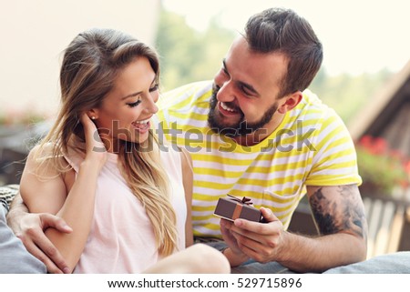 Picture showing happy couple with present sitting outdoors