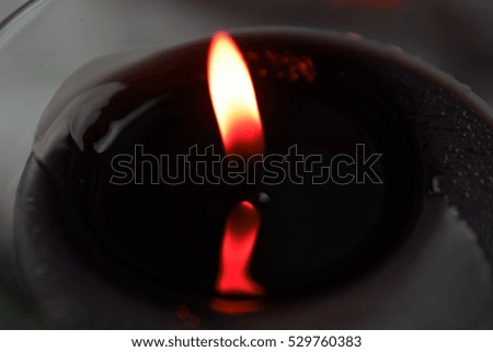 close up of a candle light, top view, copy space. golden flame. Black wax, burning concept. zen meditation concept, spa concept. A close-up of the flame of a candle with dark background. religion. 