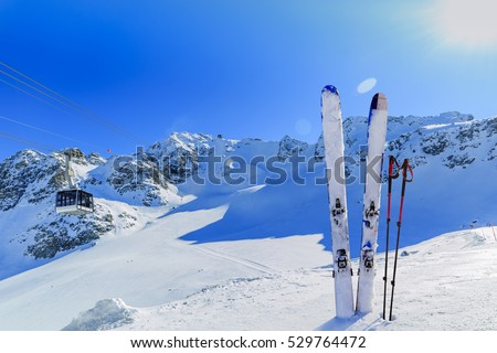 Ski winter season - mountains, cable car and ski equipments on ski run, cable car ski lift in background.