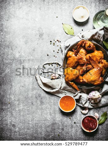 Smoked chicken wings with sauce. On a stone background.