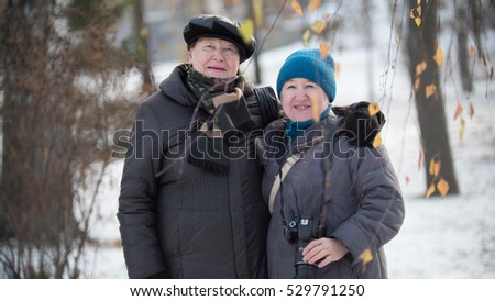 Two happy senior woman with photo camera at winter park outdoors