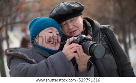 Two senior woman looking to they self photo camera and smiling at winter day, outdoor