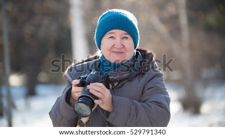 Senior woman with photo camera at winter day, outdoor