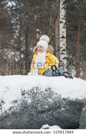 girl sitting on a large rock in the park on a winter day