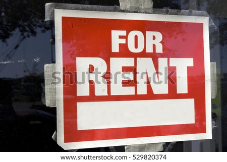 Red and white For Rent Sign taped to inside of window