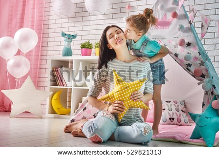 Happy loving family. Mother and her daughter girl play in children room. Funny mom and lovely child having fun indoors. 