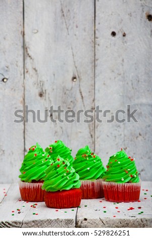 Bright red cupcakes in the form of Christmas trees on a white wooden background