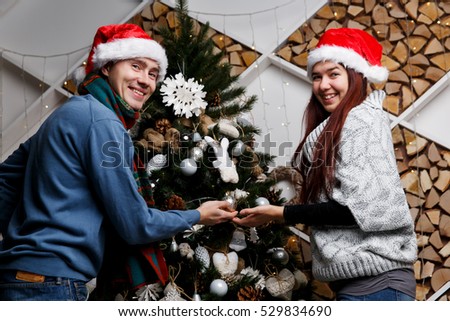 Cheerful pair adorning Christmas pine