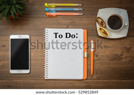 Text to do and Business (school) accessories (notebook, diary, mobile phone, cactus, pens, pencils) and title,  a cup of coffee on a wooden table. Top view.