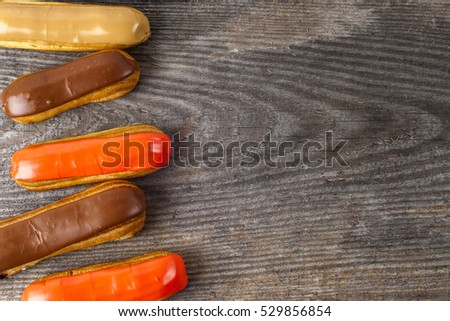 Tasty eclairs on table on rustic wooden background, close up. Copy space for text.
