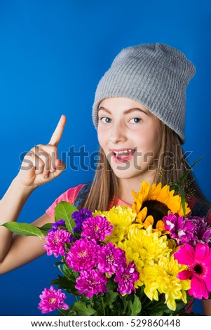Attractive young girl with a bouquet of colorful flowers. Blue background