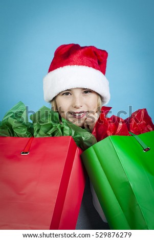 Young girl with santa hat and shopping bag shot isolated on blue background