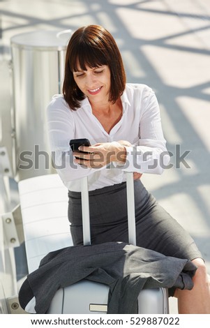 Portrait of business woman traveler waiting with phone and suitcase
