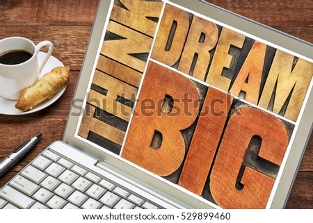 think and dream big motivational phrase -  word abstract in letterpress wood type printing blocks on a laptop screen with coffee
