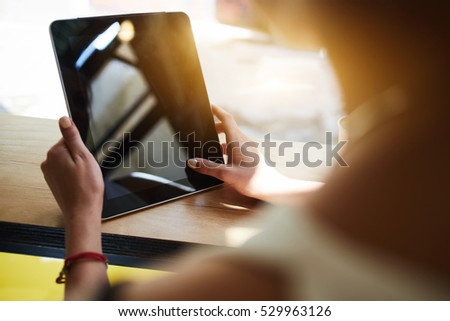 Close up hipster girl using online banking or shopping on web store via digital device with mock up screen for advertising. Female person using wireless connection via modern portable touch pad