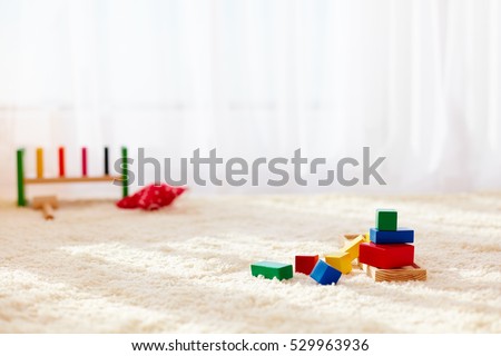 wooden toy bricks strewn on the carpet in playroom, at sunny day