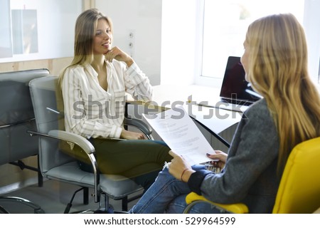 International female student discussing with her teacher strategy of coursework about marketing, making report in modern university coworking space with laptop computers and free internet access