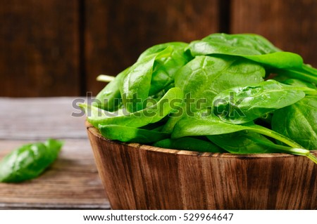 Fresh mini spinach in a wooden bowl on old wooden table