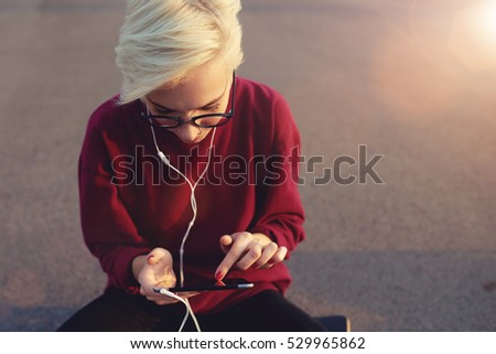Young female freelancer making photo review and listening to music using 4G connection on modern device. Woman working on tablet with copy space background where you can put advertising text message
