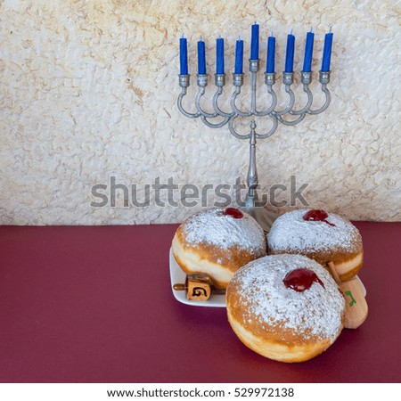 Jewish menorah with candles and sweet donuts are traditional symbols for Hanukkah holiday