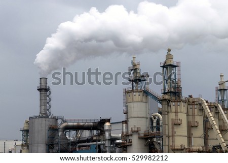Industrial facility view with factory chimney and smoke