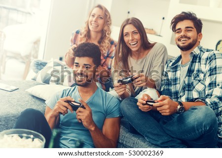 Excited friends playing video games at home. Royalty-Free Stock Photo #530002369