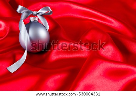 Silver christmas ball on a red silk cloth