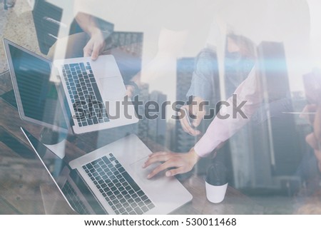 Double exposure of young coworkers working together on new startup project in modern place.Business people using mobile gadgets.Skyscraper office building at the blurred background.Horizontal,flare