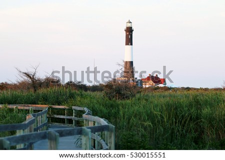 The Fire Island Lighthouse with a boardwalk and green beach grass in the picture