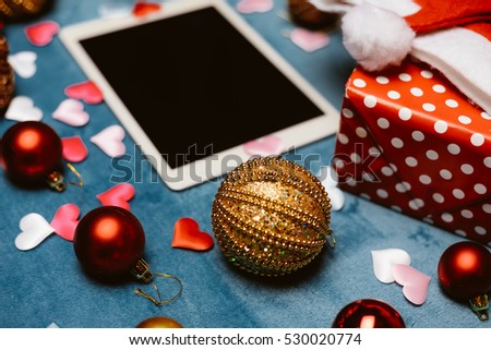 Defocused blurred mobile tablet computer with Santa Claus hat and festive Christmas decoration flat lay closeup. Online shopping background. Top view screen mockup image