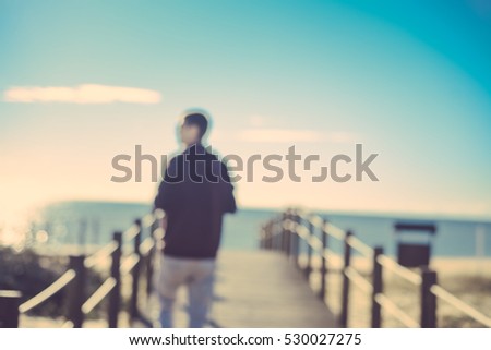 Unrecognizable silhouette back view of photographer taking natural landscape photo on wooden bridge sunny ocean blue sky outdoors background