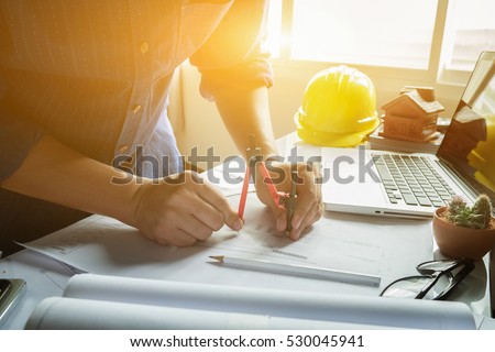 Architect working on blueprint.engineer inspective in workplace - architectural project, blueprints,ruler,calculator,laptop and divider compass. Construction concept. Engineering tools,selective focus Royalty-Free Stock Photo #530045941