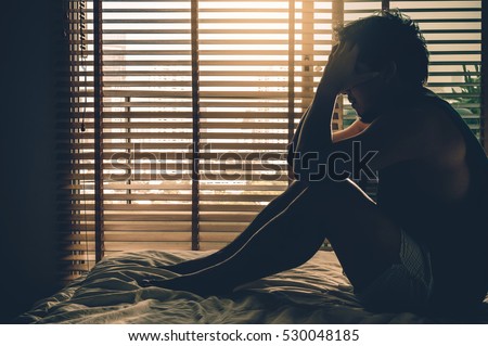 depressed man sitting head in hands on the bed in the dark bedroom with low light environment, dramatic concept Royalty-Free Stock Photo #530048185