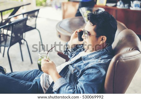 Young man with smartphone smiling relaxing at cafe.