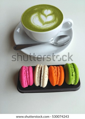 A cup of hot matcha latte so delicious with macaroons on white 