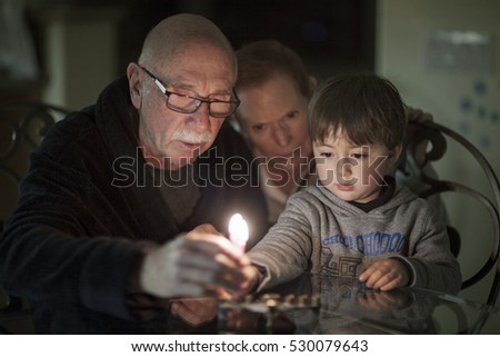 Jewish Family lighting Hanukkah Candles in a menorah for the holdiays