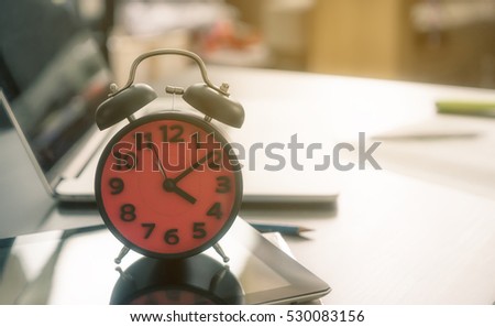 Time to go home. The alarm clock counting at the end of the day on an office table.