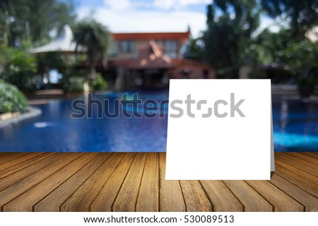 White card put on wooden desk or wooden floor on blurred swimming pool at resort background.use for present or mock up your product.product display template.Business presentation.clipping path include
