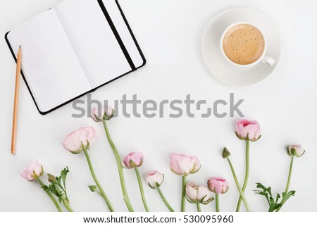 Beautiful spring Ranunculus flowers, empty notebook and cup of coffee on white desk from above. Greeting card. Breakfast. Pastel color. Clean space for text. Flat lay styling