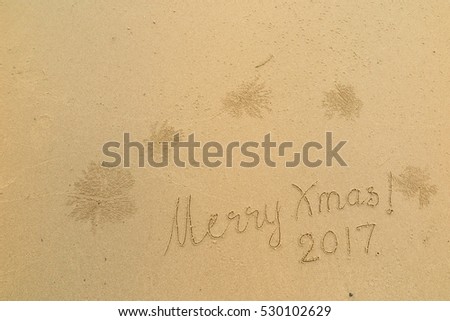 written words "Merry Xmas! 2017" on sand of beach