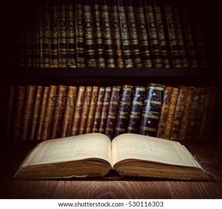 Open old book on a bookshelf background. Selective focus.